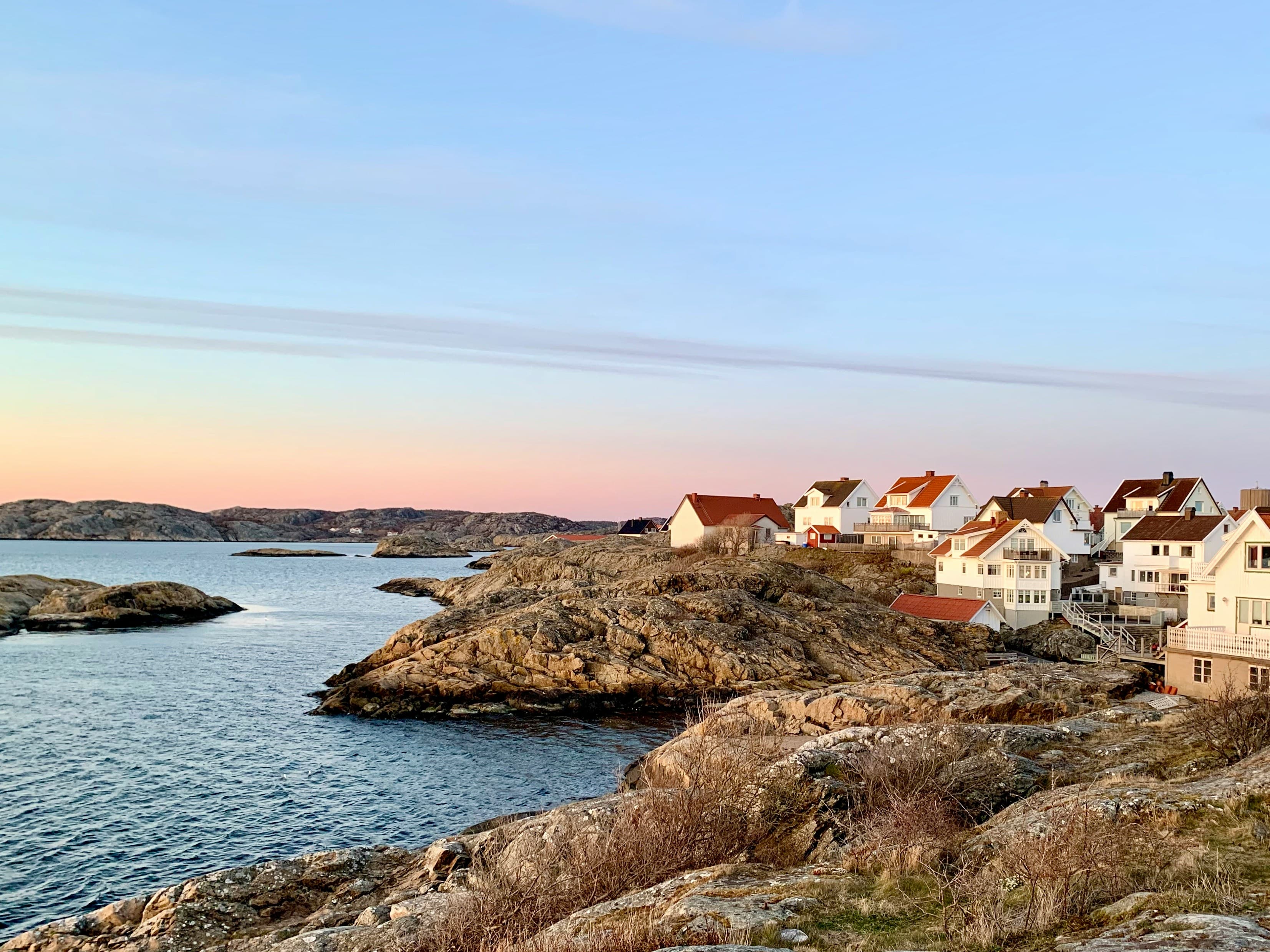 Vita hus på klippig kustlinje i solnedgång